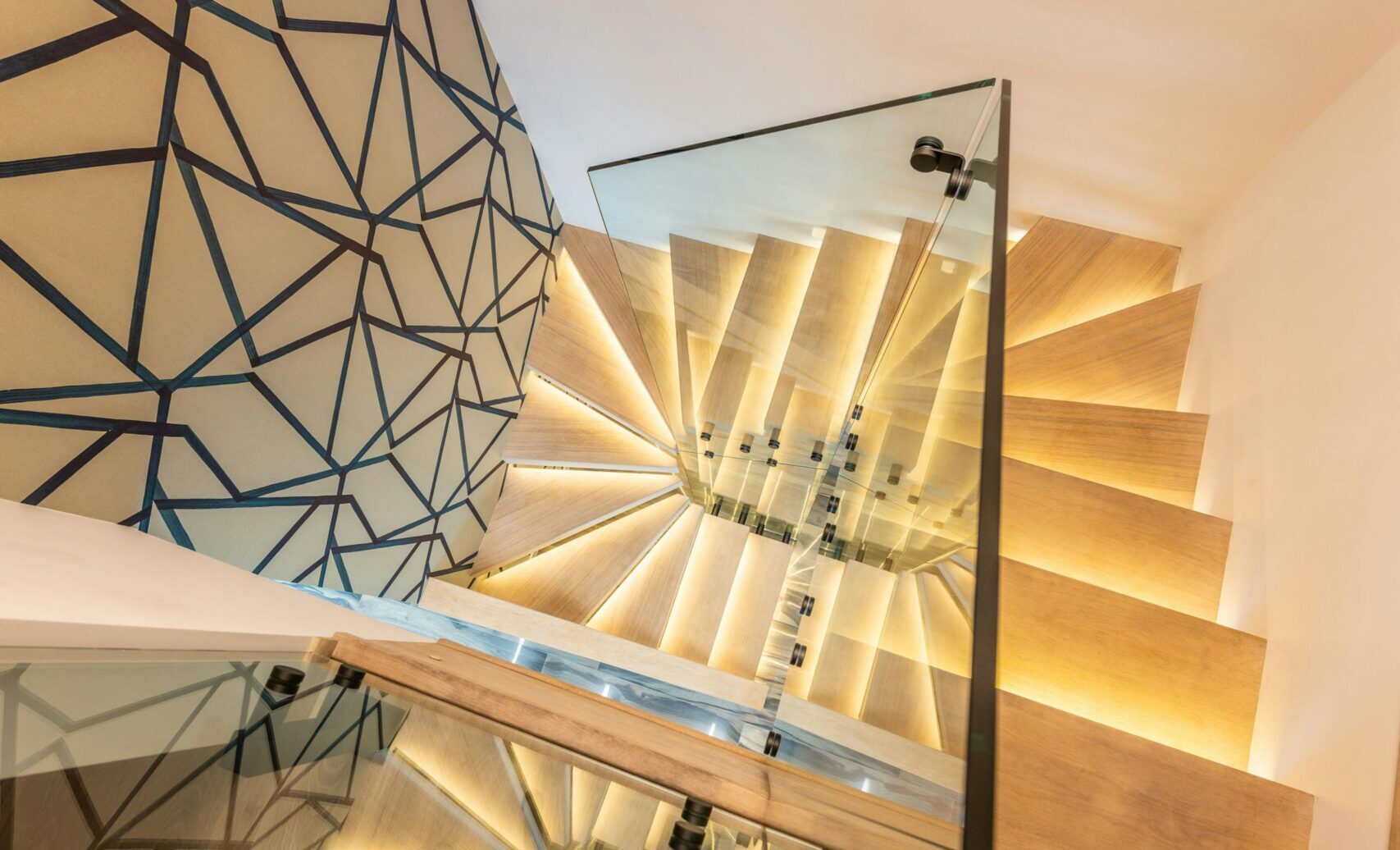 Traprenovaties 2 From above of modern glowing wooden staircase with transparent glass railing in house