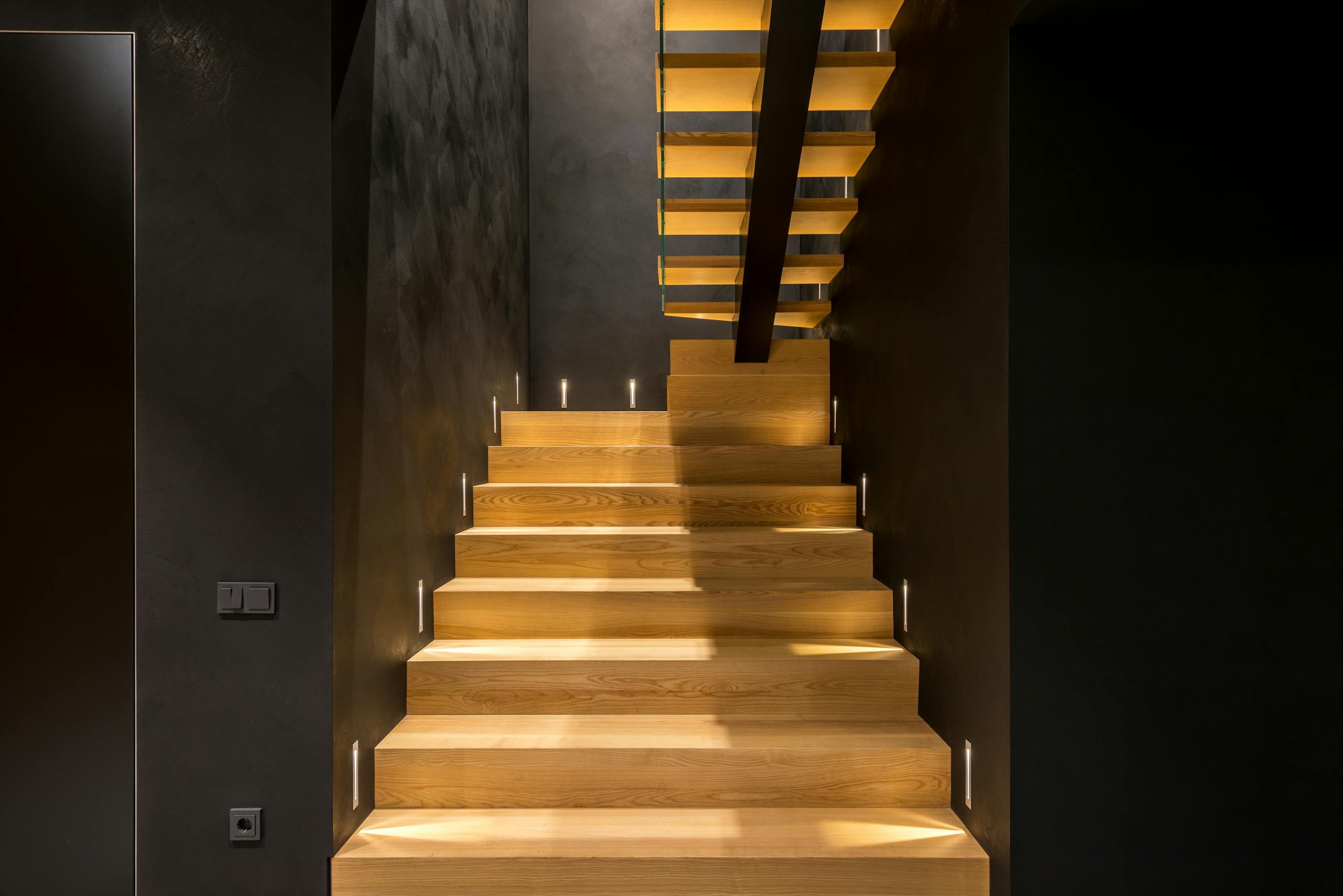 Traprenovaties 3 Interior of contemporary multistory apartment with creative wooden stairs and straight dark walls